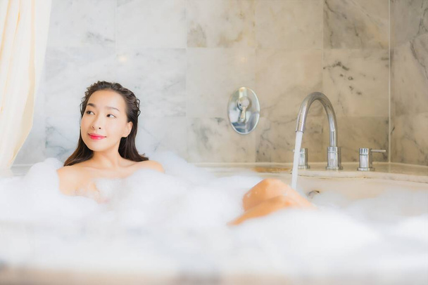 Retrato bonito jovem asiático mulher relaxar tomar um banho na banheira no banheiro interior
 - Foto, Imagem