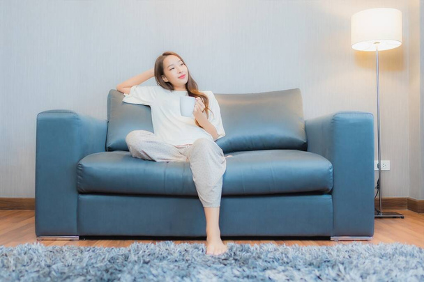 Ritratto bella giovane donna asiatica rilassarsi sul divano in salotto interno - Foto, immagini