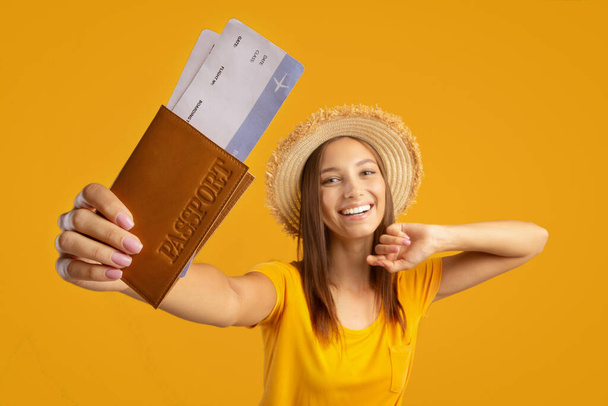 Χαρούμενη γυναίκα με καλοκαιρινό καπέλο με διαβατήριο και εισιτήρια - Φωτογραφία, εικόνα