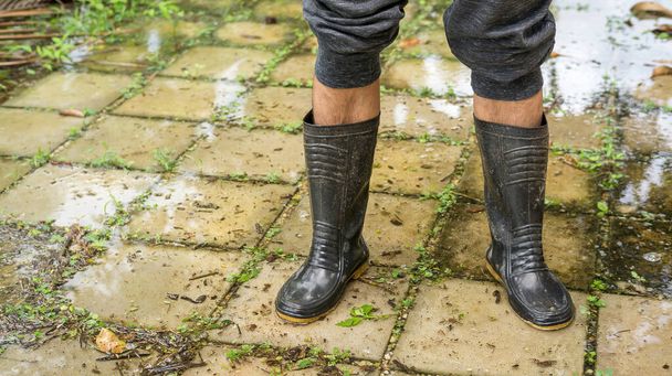Los hombres usan botas negras para una inundación. - Foto, imagen
