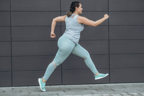 Жирная женщина бегает трусцой, занимается спортом для потери веса, проблемы ожирения. - Фото, изображение
