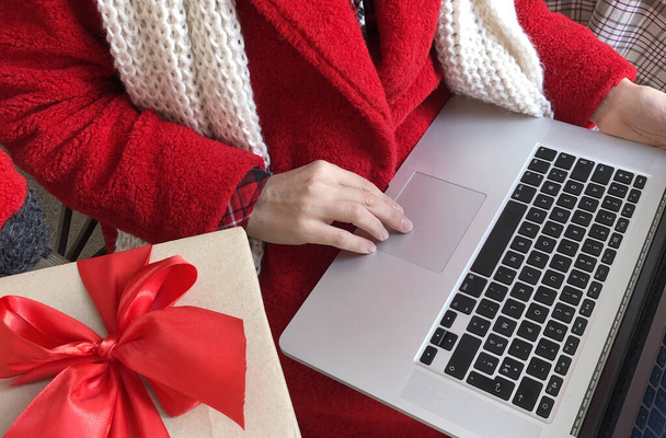 Kobieta ubrana w czerwone futro za pomocą laptopa w przeddzień świąt Bożego Narodzenia i Nowego Roku. - Zdjęcie, obraz