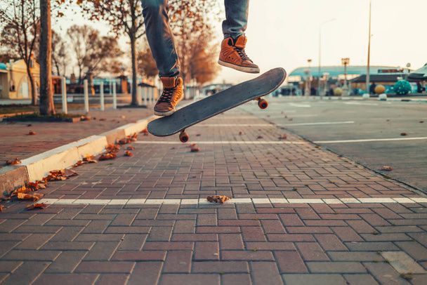 Skateboarding. Muž předvádí Ollieho kousek na skateboardu. Prkno do vzduchu. Detailní záběr na nohy. Ulice na pozadí. - Fotografie, Obrázek