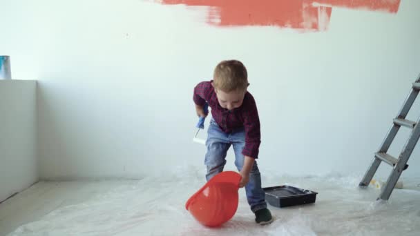 Kleiner Junge hebt orangefarbenen Schutzhelm auf den Kopf - Filmmaterial, Video