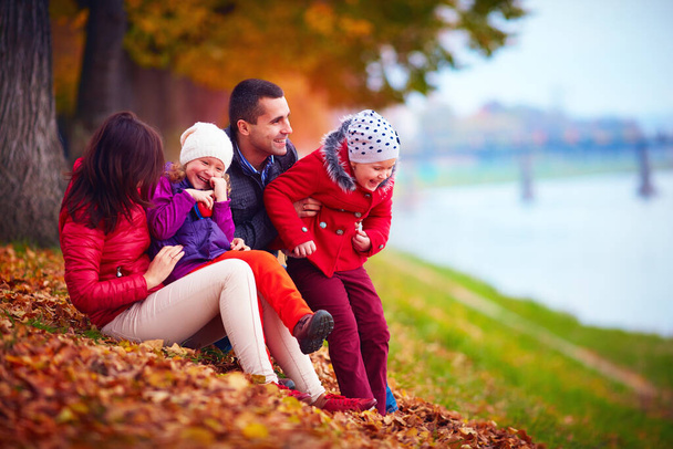 smiling family having fun among fallen leaves in autumn park - Φωτογραφία, εικόνα