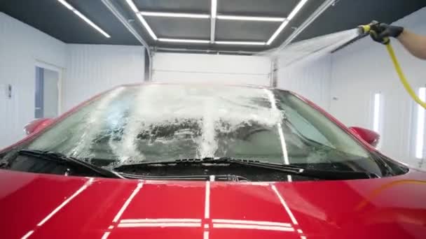 Mann wäscht rotes Auto in Waschanlage. - Filmmaterial, Video