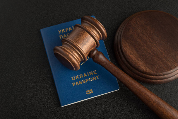 Rechter hamer en Oekraïense paspoort op zwarte achtergrond. Paspoort van Oekraïne. Burgerschap verkrijgen. - Foto, afbeelding