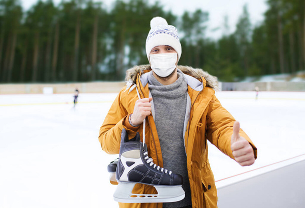 man in mask showing thumbs up on skating rink - Foto, imagen