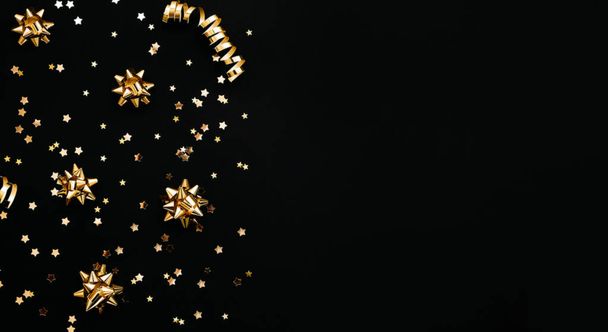 Различные золотые праздничные предметы на черном фоне. Праздничный концептуальный рождественский или новогодний баннер. Ближайшее пространство для копирования. - Фото, изображение