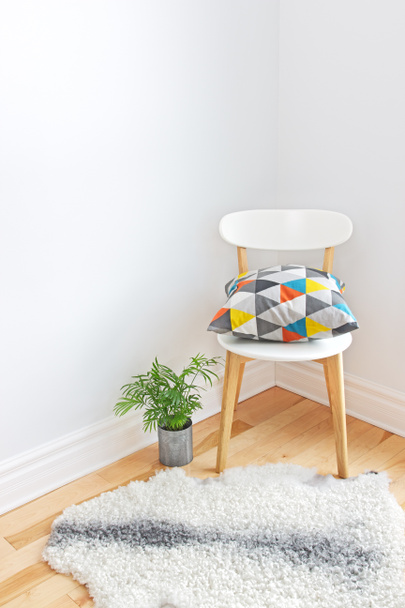 καρέκλα με φωτεινά μαξιλάρι και sheepskin κουβέρτα στο πάτωμα - Φωτογραφία, εικόνα
