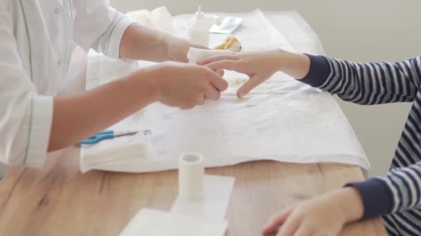 Μια γυναίκα γιατρός κάνει ένα επίδεσμο δάχτυλο σε ένα έφηβο αγόρι - Πλάνα, βίντεο