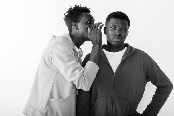 Στούντιο πλάνο των δύο νεαρών Αφρικανών ως φίλοι μαζί σε λευκό φόντο σε μαύρο και άσπρο - Φωτογραφία, εικόνα