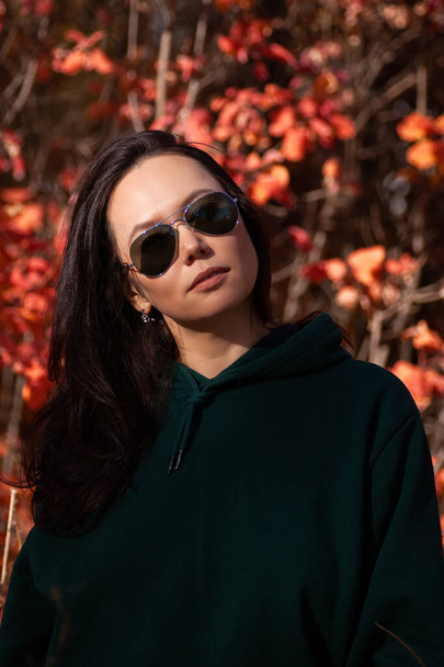 portrait of a beautiful asian young woman in sunglasses in the autumn forest at sunset - Fotó, kép