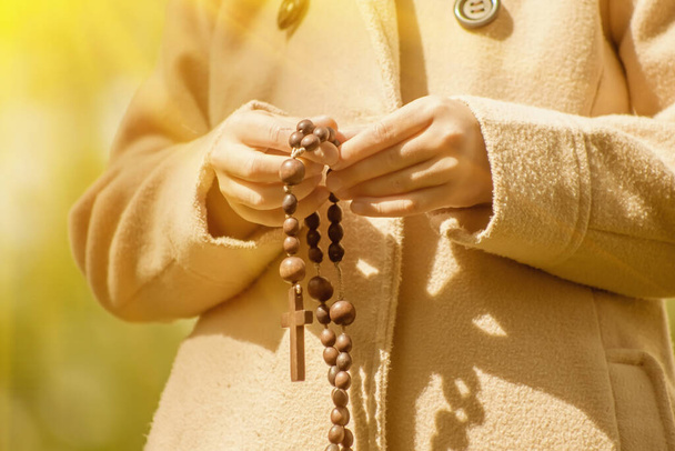 Молода дівчина молиться з дерев'яним розарієм. крупним планом
. - Фото, зображення