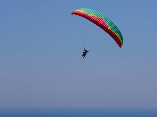 Fliegende Tandem-Gleitschirme am Himmel über dem Meer und in der Nähe der Berge, schöner Meerblick - Foto, Bild