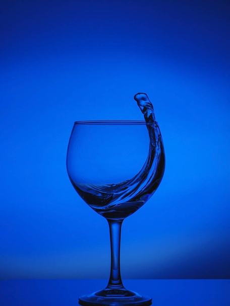Splash astratto allettante dell'acqua fredda fresca chiara su sfondo sfumato del colore blu sulla superficie riflettente - Foto, immagini