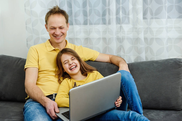 Babam ve kızım dizüstü bilgisayara bakıyorlar ve harika vakit geçiriyorlar. Mutlu aile kavramı. - Fotoğraf, Görsel
