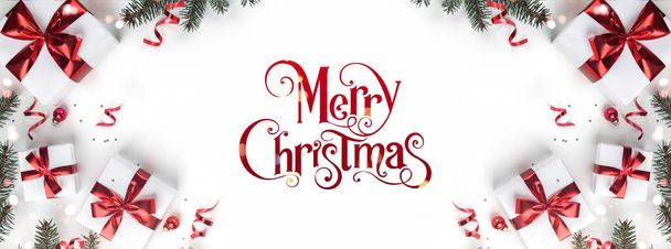 ギフトボックス、リボン、赤い装飾、モミの枝、ボケ、輝きとコンフェッティと白い背景にメリークリスマステキスト。クリスマスと新年の挨拶カード、ボケ、光。フラットレイアウト、トップビュー - 写真・画像