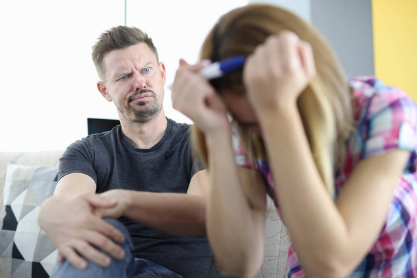 Meglepett férfi néz a nő a fejét lehajtott és a gazdaság terhességi teszt - Fotó, kép