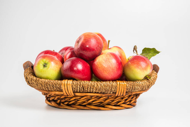 Bright multi-colored fresh apples in a wicker basket on a white background. Selective focus. - Foto, immagini