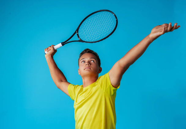 Young man tennis player in sportswear posing against blue background - Foto, Bild