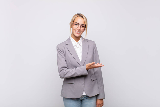 young businesswoman smiling cheerfully, feeling happy and showing a concept in copy space with palm of hand - Фото, зображення