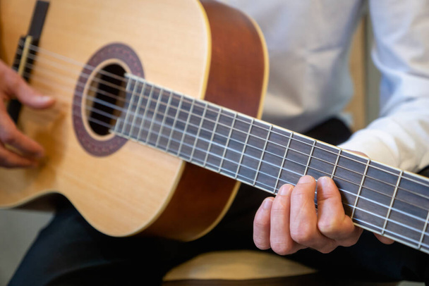 Classical guitar - Guitarist playing acoustic guitar in studio - selective focus close-up of the fingerboard and hand  - Фото, изображение