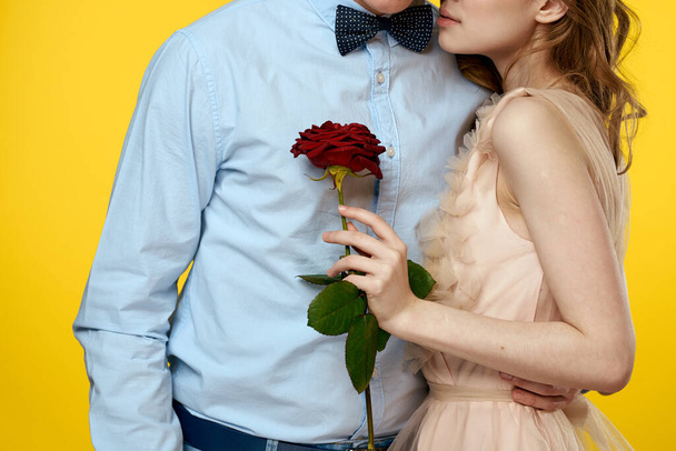 Enamored man and woman with red rose on yellow background cropped view close-up romance - Φωτογραφία, εικόνα