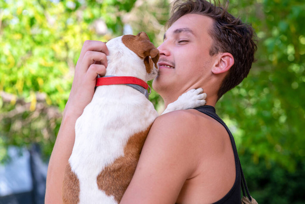 Yakışıklı genç adam köpeğini kollarında tutuyor.. - Fotoğraf, Görsel