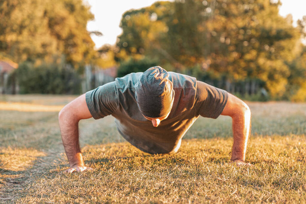 Sport i joga. Mężczyzna w stroju sportowym pompki na trawie. - Zdjęcie, obraz