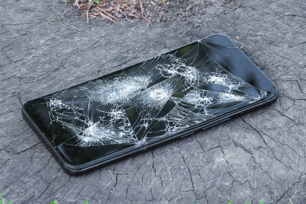 Kalın bir ağaç kütüğündeki kurşundan çıkan bir delikle kırılmış bir telefon. - Fotoğraf, Görsel