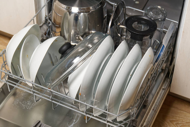 Schmutziges Geschirr in offener integrierter Spülmaschine. voll beladene Geschirrspüler bereit zum Waschen. Offene Geschirrspülmaschine mit verschmutztem Geschirr vor dem Waschen. - Foto, Bild