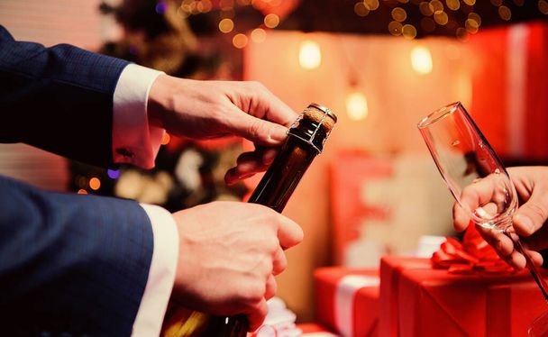 Drink champagne or sparkling wine. Celebrate new year with champagne. Toast and cheers concept. Lets celebrate. Male hands opening champagne bottle pouring glasses christmas decorations background - Φωτογραφία, εικόνα