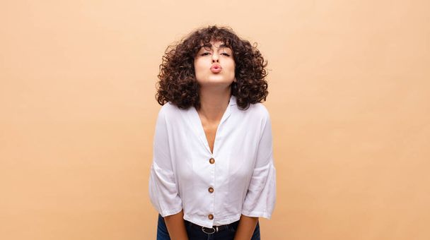 Woman pressing lips together with a cute, fun, happy, lovely expression, sending a kiss - Fotó, kép