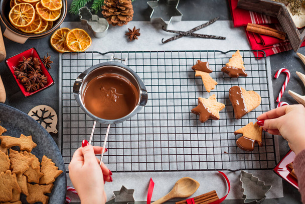 cropped shot of woman glazing Christmas biscuits with liquid chocolate on a kitchen table - Φωτογραφία, εικόνα