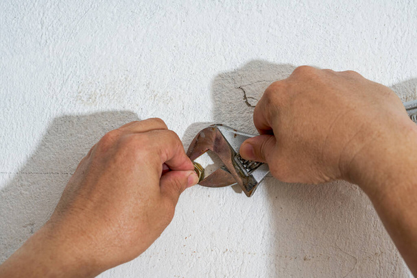 Dělník otáčí šrouby na stěně klíčem. - Fotografie, Obrázek