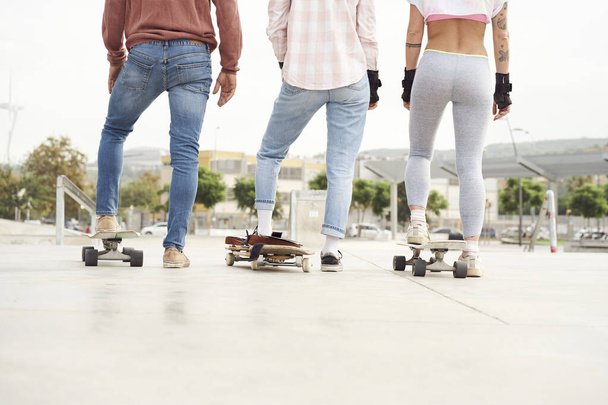 Fiatal korcsolyázók lába hátulról. Készen állnak a korcsolyázásra a skateparkban.. - Fotó, kép