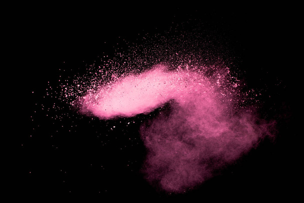 Рожеві частинки пилу сплескаються на чорному тлі. Рожевий порошок сплеск
. - Фото, зображення