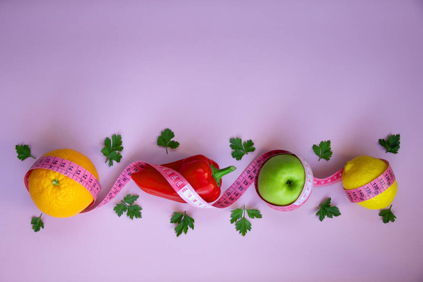 Layout di tendenza con frutta fresca, verdura e verdura con nastro di misurazione su sfondo rosa. Diete intermittenti, keto, disintossicanti e magre. Concetto nutrizionale sano. Posa piatta, spazio di copia. - Foto, immagini