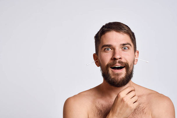 Hombre barbudo con hombros desnudos hisopos de algodón higiene cuidado corporal - Foto, Imagen