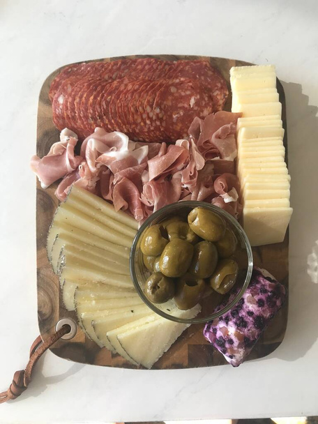 Прекрасная доска с восхитительным мясом, сыром и оливками - Фото, изображение