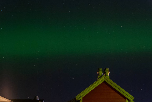 Маленький зеленый северный свет в ночном небе над деревянным домом - Фото, изображение