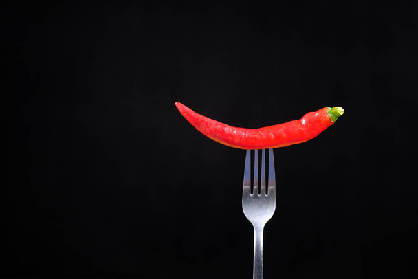 red chili pepper on the fork on black background . - Fotoğraf, Görsel