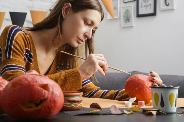 自宅でハロウィンの飾りを作っている若い女性。秋｜DIY Craft. - 写真・画像