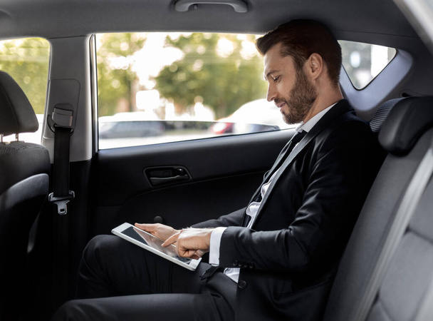Wealthy man working on digital pad while going to airport - Foto, imagen