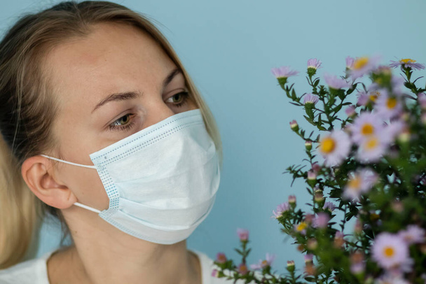 Retrato de uma jovem em uma máscara médica, em um fundo azul - Foto, Imagem