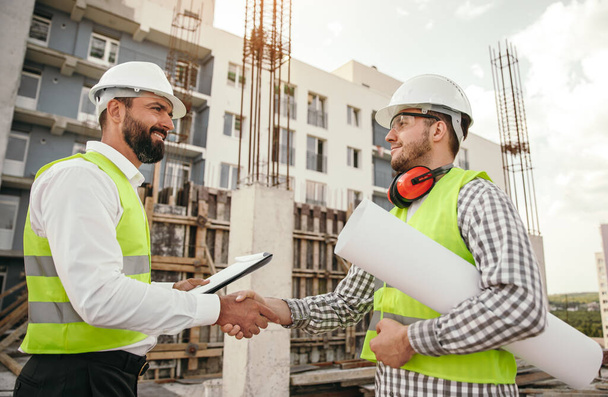 Professional builders shaking hands on construction site - Foto, afbeelding