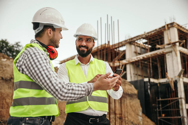 Male builders using smartphone during work - Foto, immagini