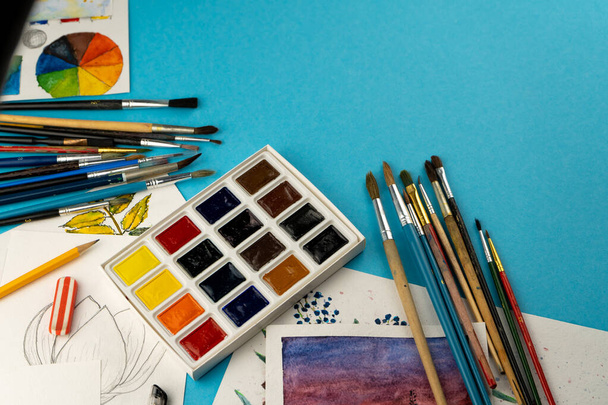 Watercolor paints and brushes. Artist's workplace and desk. Color palette. Drawing background. Place for your text. - 写真・画像