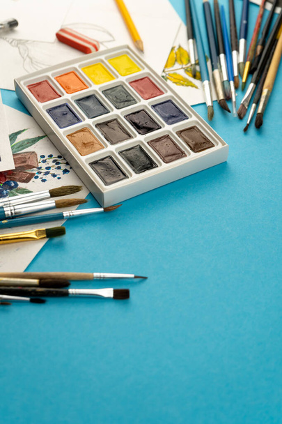 Watercolor paints and brushes. Artist's workplace and desk. Color palette. Drawing background. Place for your text. - 写真・画像